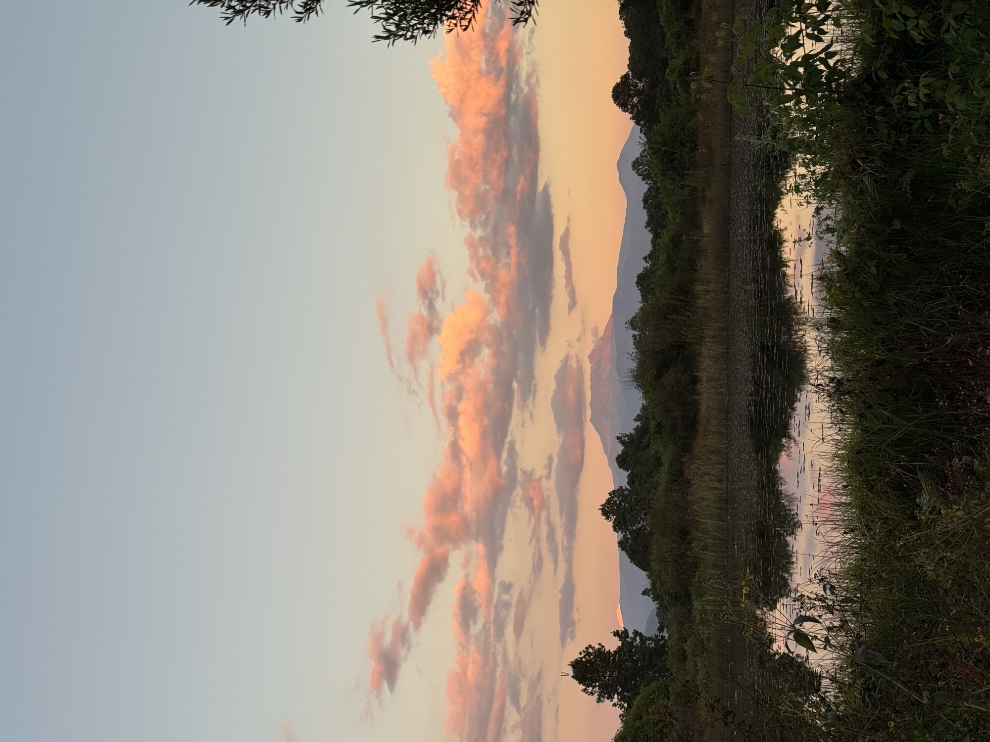 A mountain lake at sunset, pink clouds reflected in the still water
